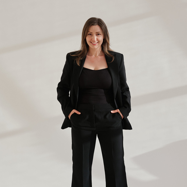 Tanja Grill, Gründerin von TANOLARA, Strategie & Design Studio blickt in die Kamera, vor hellem minimalistischen Hintergrund.
